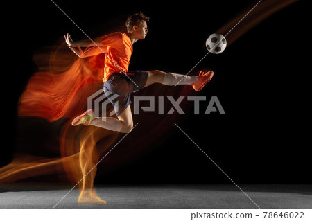 Young caucasian male football or soccer player kicking ball for the goal in mixed light on dark background. Concept of healthy lifestyle, professional sport, hobby. Young caucasian male football or soccer player kicking ball for the goal in mixed light on dark background. Concept of healthy lifestyle, professional sport, hobby. 78646022