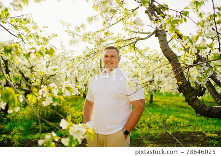 portrait of a strong adult male in a flowering garden. businessman farmer. portrait of a strong adult male in a flowering garden. businessman farmer. 78646025