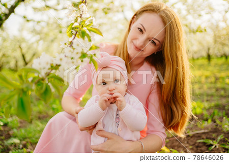 mother with baby in arms in flowering garden. surgery for child with cleft lip. mother with baby in arms in flowering garden. surgery for child with cleft lip. 78646026