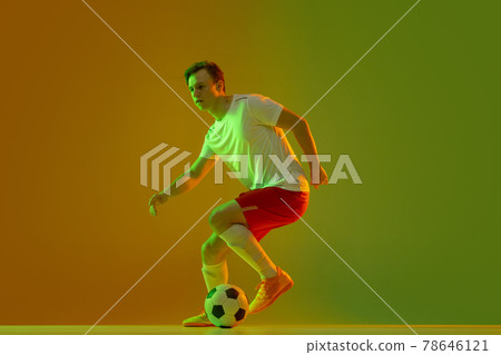 One male soccer football player in action and motion isolated on gradient green yellow background in neon light One male soccer football player in action and motion isolated on gradient green yellow background in neon light 78646121