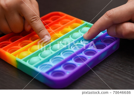 Children hands are competing for the speed of clicking on a color pop it Children hands are competing for the speed of clicking on a color pop it 78646686