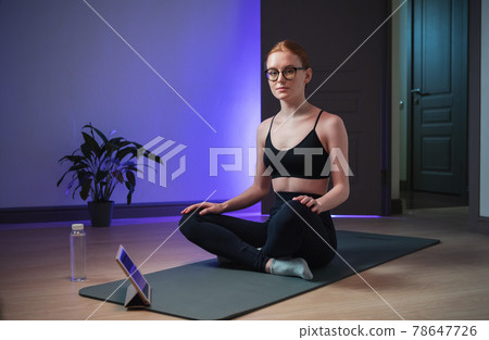An experienced yoga coach conducts an online yoga class, the girl shows her students how to properly sit in the lotus position for meditation 78647726