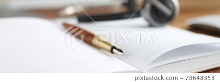 On desktop is diary with pen and headphones 78648353