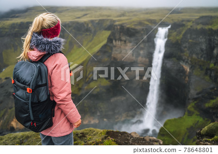 Woman with backpack and lilac jacket enjoying Haifoss waterfall of Iceland Highlands in Thjorsardalur Valley Woman with backpack and lilac jacket enjoying Haifoss waterfall of Iceland Highlands in Thjorsardalur Valley 78648801