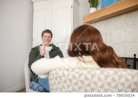 Laughing man with coffee and woman back Laughing man with coffee and woman back 78650034