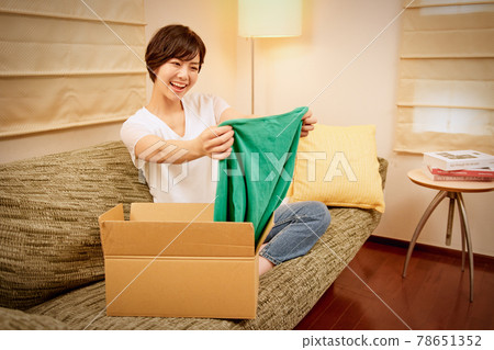 一位面帶微笑的年輕女子，很高興收到郵購商品 78651352