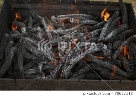 Corn ears in a barbeque fire pit. flaming hot close up Corn ears in a barbeque fire pit. flaming hot close up 78652118