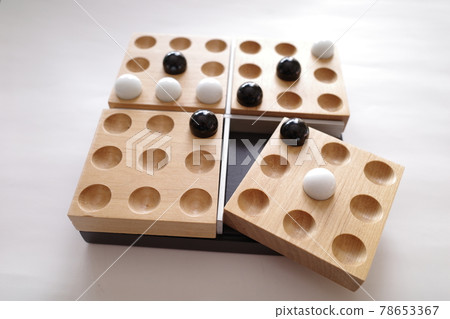 A board game where white and black marbles are lined up on a wooden tray 78653367