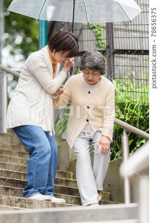 Senior long-term care female rainy season umbrella 2 people stairs 78656375