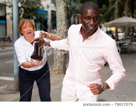 Man trying to thieve female handbag 78657079