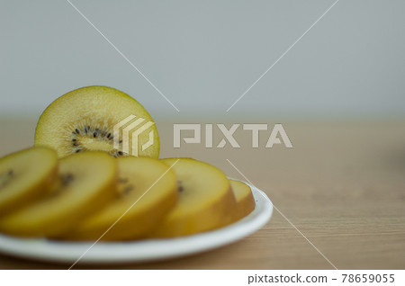 Slices of golden kiwi with yellow pulp on white plate on the kitchen. Exotic fruits, healthy eating concept Slices of golden kiwi with yellow pulp on white plate on the kitchen. Exotic fruits, healthy eating concept 78659055