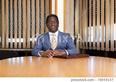 Confident businessman sitting with briefcase of documents in meeting room Confident businessman sitting with briefcase of documents in meeting room 78659137
