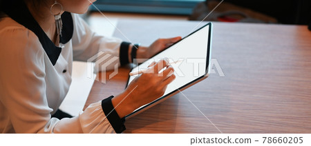 Cropped shot of young female working on her project with mock up tablet computer in office. Cropped shot of young female working on her project with mock up tablet computer in office. 78660205
