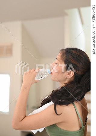 Beautiful young woman drinking a fresh of water at home. 78660453