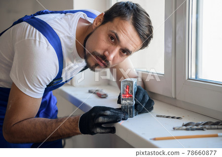 Architect uses a laser level to measure the distance 78660877