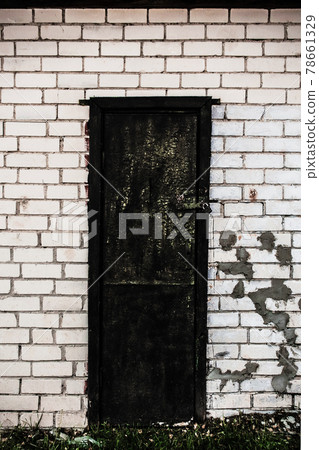 Old spooky wooden door with a lock in white brick wall Old spooky wooden door with a lock in white brick wall 78661329