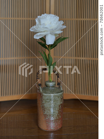 A single Japanese-style white flower in a pottery vase 78662001