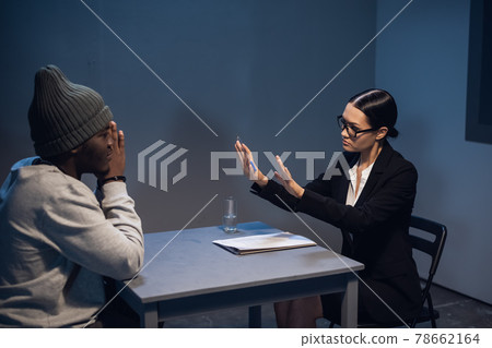 A young girl lawyer consults her client at the police station, a black guy in a cap and handcuffs. A young girl lawyer consults her client at the police station, a black guy in a cap and handcuffs. 78662164