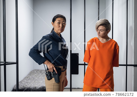 Blonde inmate in an asian women's general security prison is led out of her cell by a uniformed guard, with a holstered pistol and a walkie-talkie. Blonde inmate in an asian women's general security prison is led out of her cell by a uniformed guard, with a holstered pistol and a walkie-talkie. 78662172
