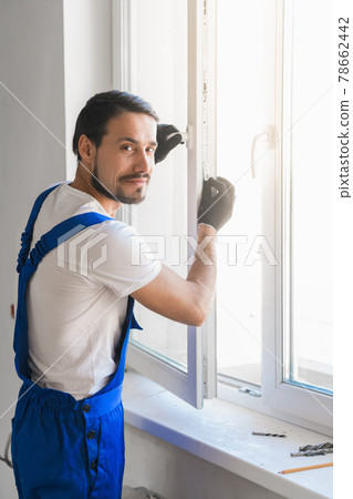 Worker installs the window and looks at the camera 78662442