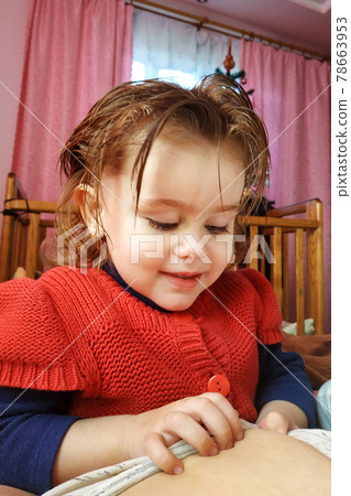 A two-year-old girl lies on the mother and drinks breast milk, the time of unity of mother and child. 78663953