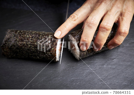 Woman chef cutting a roll of delicious sushi. Asian food concept. Healthy food 78664331