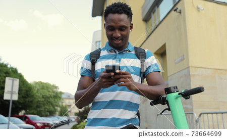 Afro american man use smartphone stand with electric scooter. Ecological transportation. Urban outdoors. 78664699