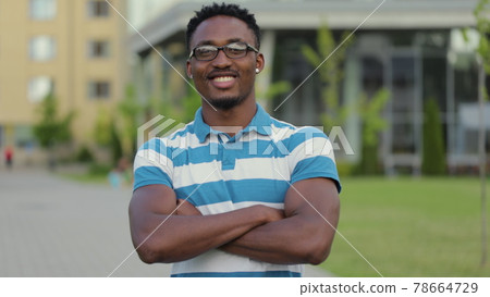 Portrait of handsome young african american man in glasses laughing cheerful at camera enjoying sunny urban city. 78664729