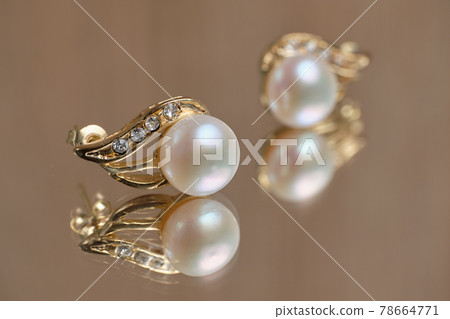 Pearl earrings on a glass table. 78664771