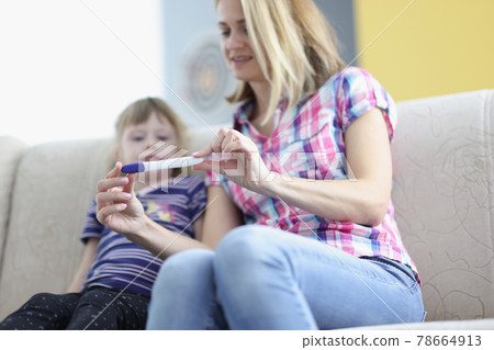 Mother showing little girl positive pregnancy test closeup 78664913