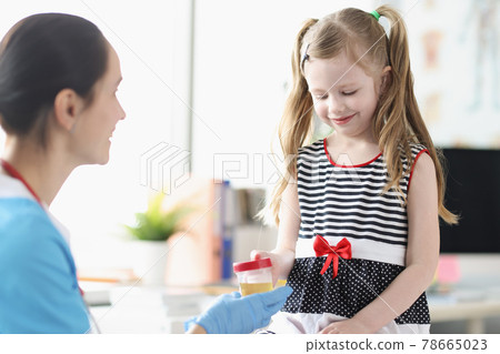 Little girl giving doctor jar of urine analysis in clinic 78665023