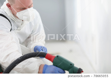 Master repairman in protective respirator and uniform painting wall with spray gun Master repairman in protective respirator and uniform painting wall with spray gun 78665055