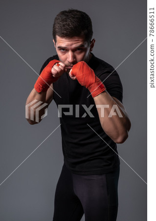 Man with wrist wraps on hands standing in orthodox boxing stance 78666511