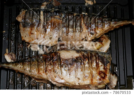 Mackerel is roasted on an electric grill. Grilled fish with lemon and salad 78670533