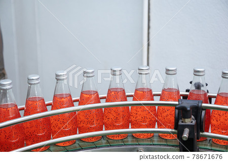 Glass bottled red juice on steel conveyor of production line in beverage processing factory 78671676