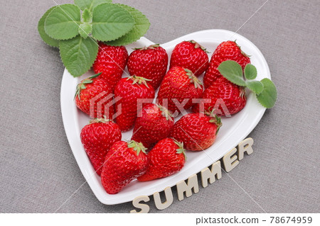 Fresh ripe delicious red strawberries and green mint leaf on a white heart-shaped plate. The word SUMMER. 78674959