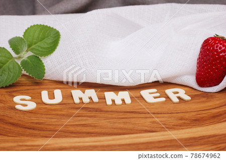 The word summer is laid out in wooden letters next to a strawberry and a mint leaf. The word summer is laid out in wooden letters next to a strawberry and a mint leaf. 78674962