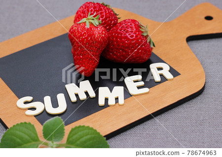 Three ripe red fresh strawberry on a wooden chopping board next to the word SUMMER in wooden letters. mint leaf Three ripe red fresh strawberry on a wooden chopping board next to the word SUMMER in wooden letters. mint leaf 78674963