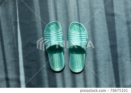 Green indoor plastic sandals on blue carpet. 78675101