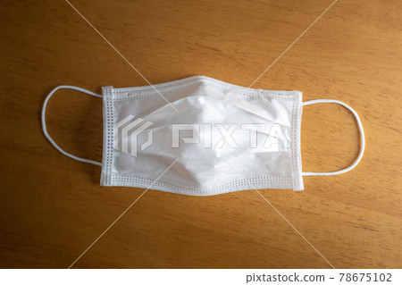White surgery face mask unfold on brown wooden table. 78675102