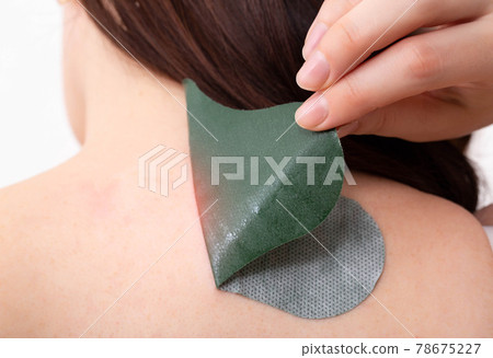 Anti-inflammatory medical herbal plaster for the treatment of spasms and pain relief of intervertebral hernias. Girl sticks a medical priest to her neck, close-up Anti-inflammatory medical herbal plaster for the treatment of spasms and pain relief of intervertebral hernias. Girl sticks a medical priest to her neck, close-up 78675227