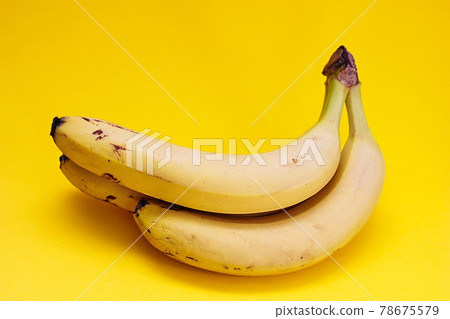 Three yellow ripe bananas on a yellow background. Three yellow ripe bananas on a yellow background. 78675579