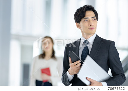 A young businessman in a suit with a smartphone working in the office 78675822