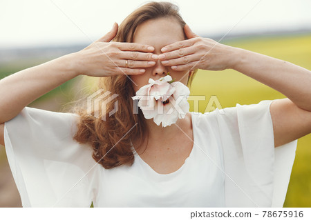 Woman in elegant dress standing in a summer field Woman in elegant dress standing in a summer field 78675916