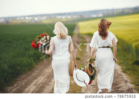 Women in elegant dress standing in a summer field Women in elegant dress standing in a summer field 78675918