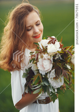 Woman in elegant dress standing in a summer field 78675931