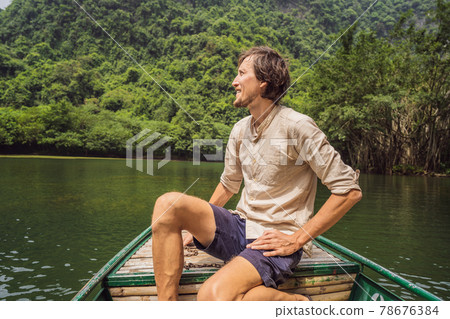 Man tourist in Trang An Scenic Landscape Complex in Ninh Binh Province, Vietnam A UNESCO World Heritage Site. Resumption of tourism in Vietnam after quarantine Coronovirus COVID 19 Man tourist in Trang An Scenic Landscape Complex in Ninh Binh Province, Vietnam A UNESCO World Heritage Site. Resumption of tourism in Vietnam after quarantine Coronovirus COVID 19 78676384