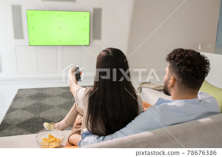 Young couple watching tv while relaxing on couch 78676386