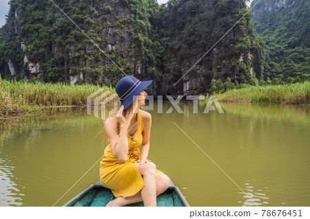 Woman tourist in boat on the lake Tam Coc, Ninh Binh, Viet nam. It's is UNESCO World Heritage Site, renowned for its boat cave tours. It's Halong Bay on land of Vietnam. Vietnam reopens borders after 78676451