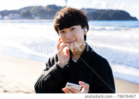一個男人在海上聽智能手機音樂 78676467